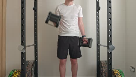 static shot of a young athletic man bicep curling dumbells in a squat rack