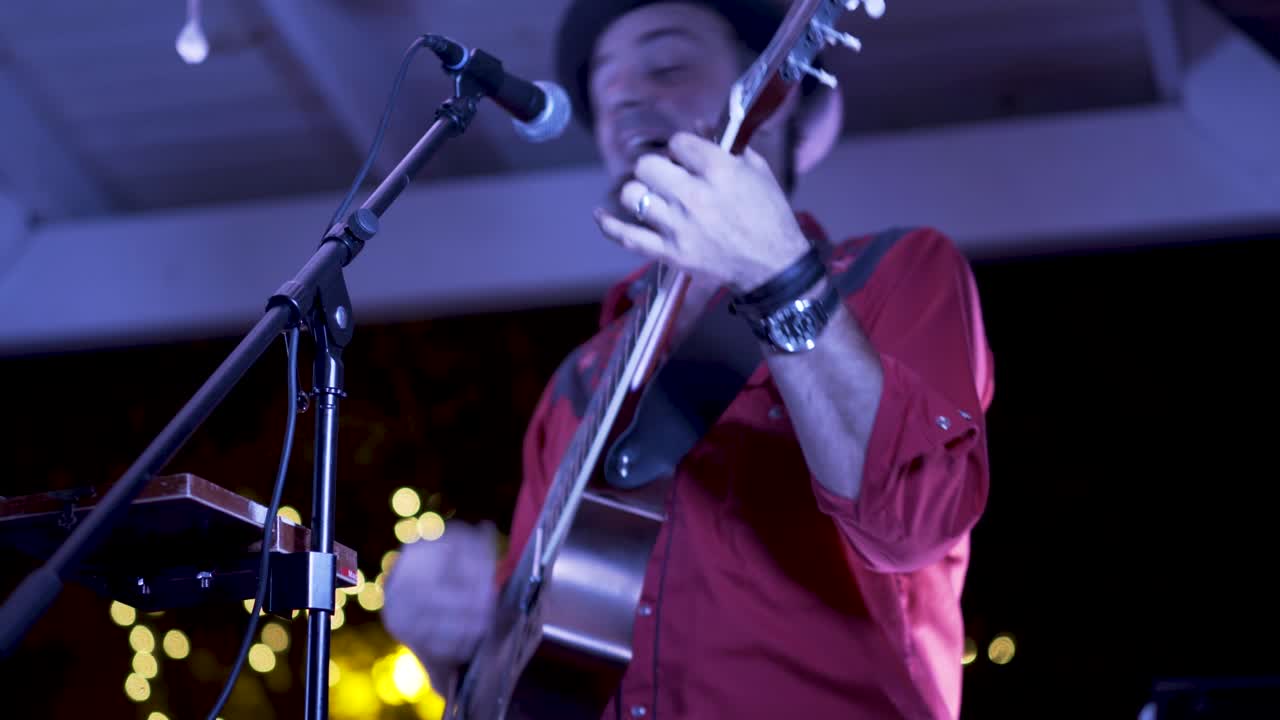 Musician performing with guitar and microphone on stage