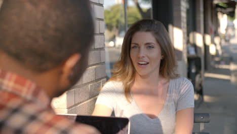 couple talking at a table outside a coffee shop