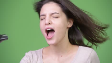 una joven hermosa cantando con un secador de pelo