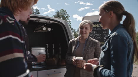 Group-Of-Young-People-Drinking-Coffee-And-Talking-With-An-Employee-Of-A-Coffee-Truck