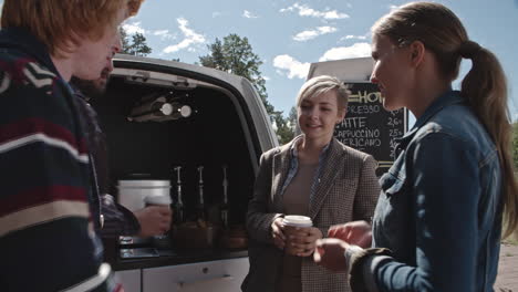 group of young people drinking coffee and talking with an employee of a coffee truck