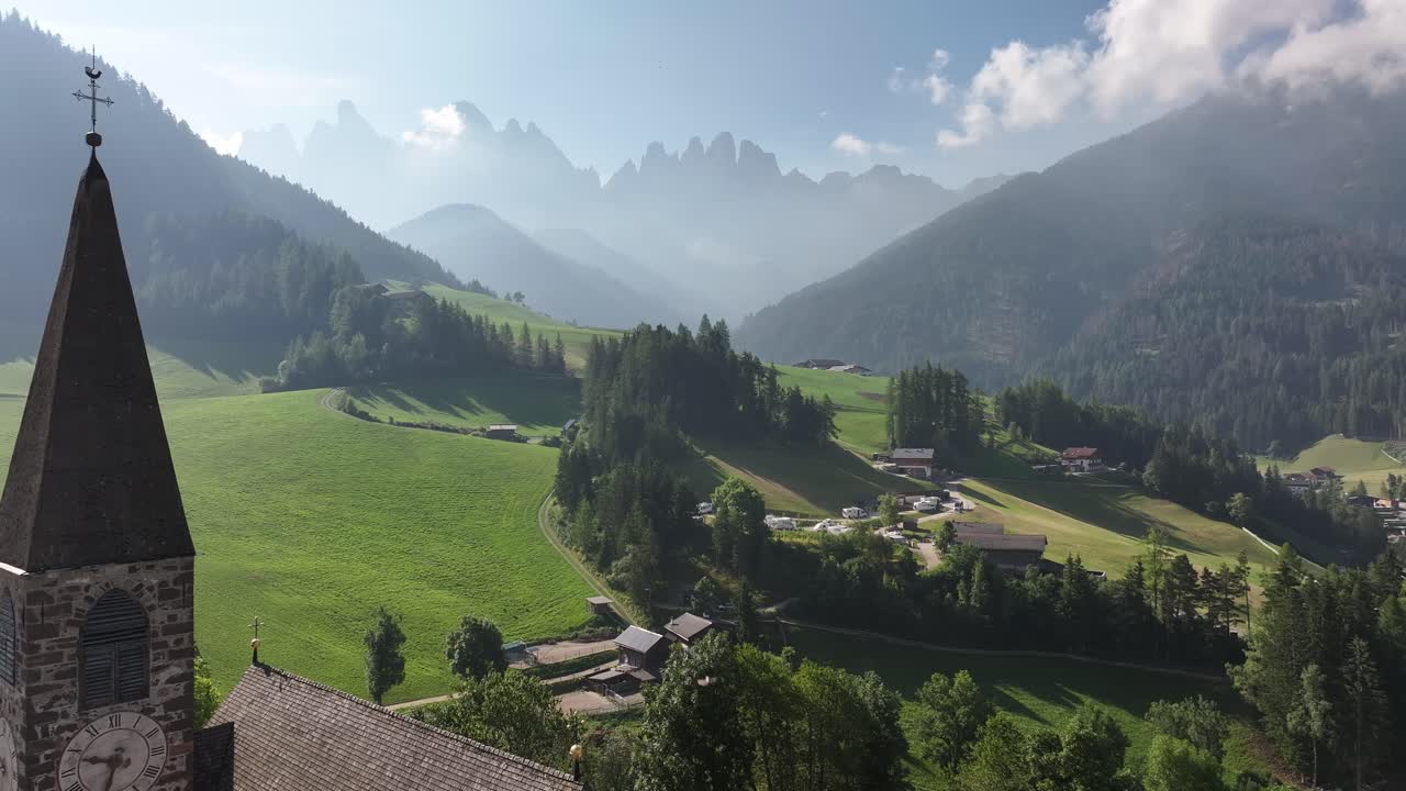 una impresionante vista aérea de una encantadora zona residencial situada contra el impresionante telón de fondo de las montañas de chiesa di santa maddalena y drei zinnen en las dolomitas, tirol del sur, funes, italia