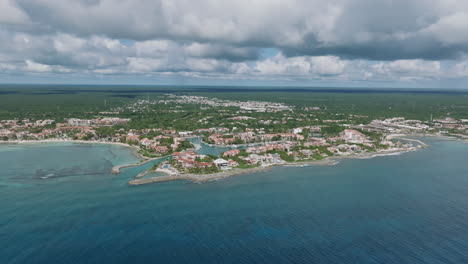 aerial view in dolly in of a coastal city, full of vibrant architecture and pristine beaches surrounded by the majestic sea in mexico