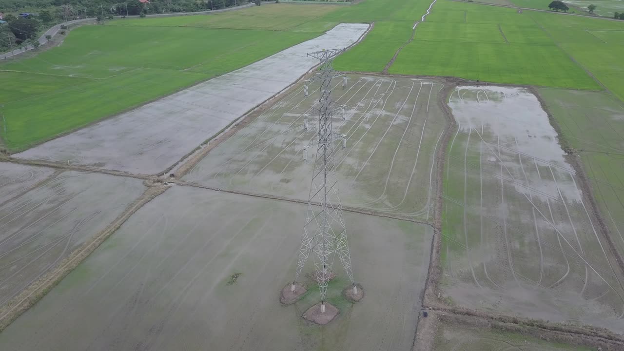 vista aérea círculo en movimiento alrededor de la columna de electricidad de alto voltaje en tierras de cultivo tailandesa