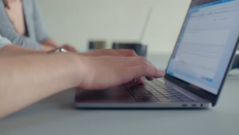 Teammates-working-in-the-office-and-typing-on-the-laptop