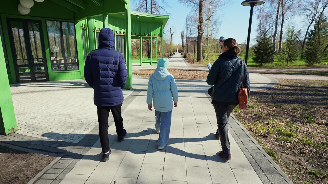 Famiglia che cammina insieme su un sentiero pavimentato in un parco soleggiato