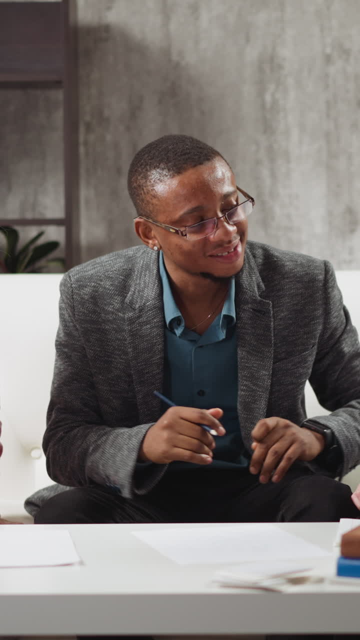 Young African-American man teaches kids to raise hand and listens answers during private English lesson with native speaker at home slow motion