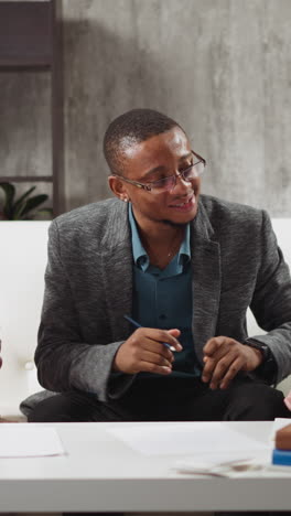 young african-american man teaches kids to raise hand and listens answers during private english lesson with native speaker at home slow motion