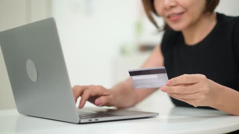 mujer asiática comprando en portátil con tarjeta de crédito