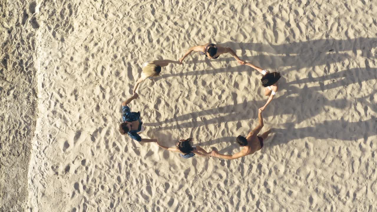 손을 잡고 해변에서 회전하는 친구들의 그룹