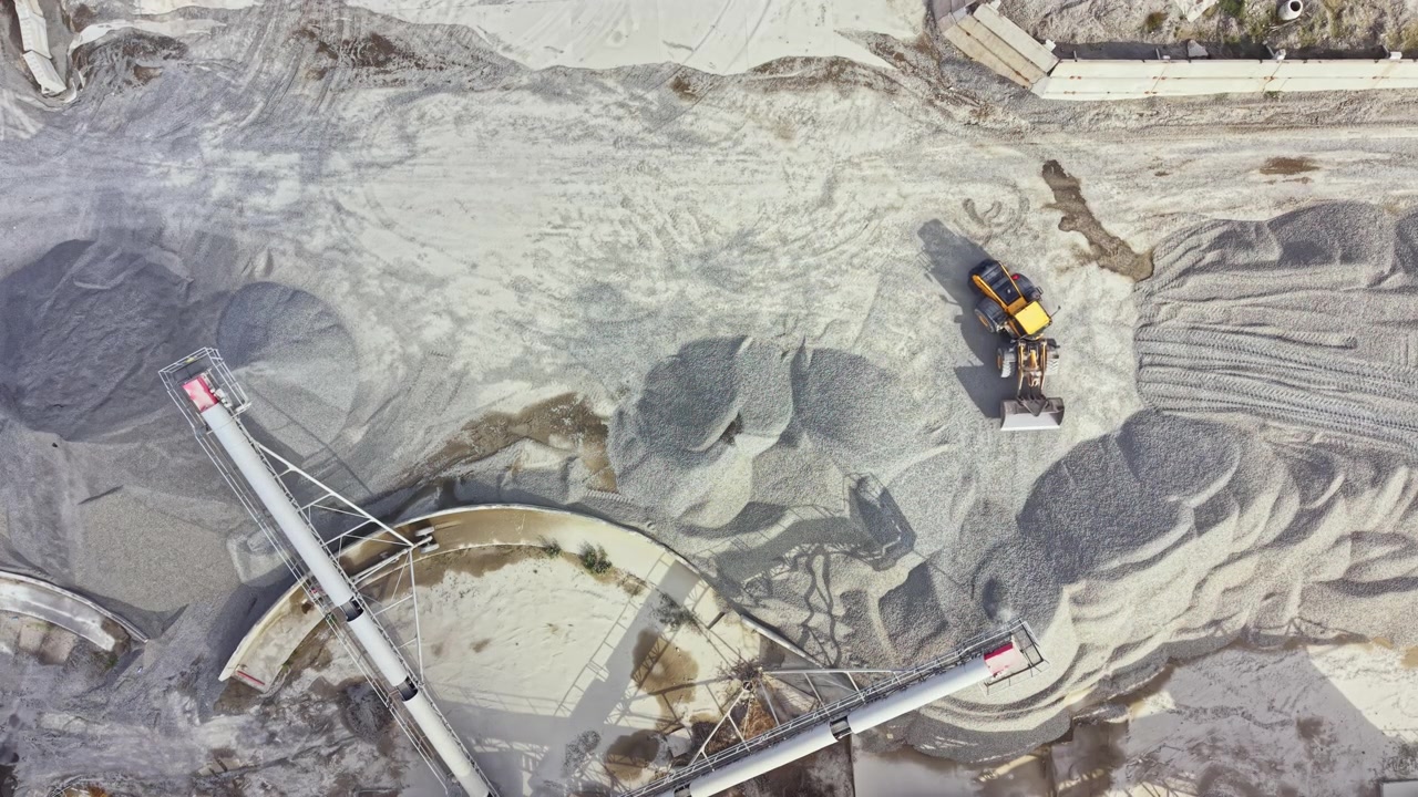 Granite quarry activity in a rock extraction site during work hours with machinery and stockpiles of material visible from above