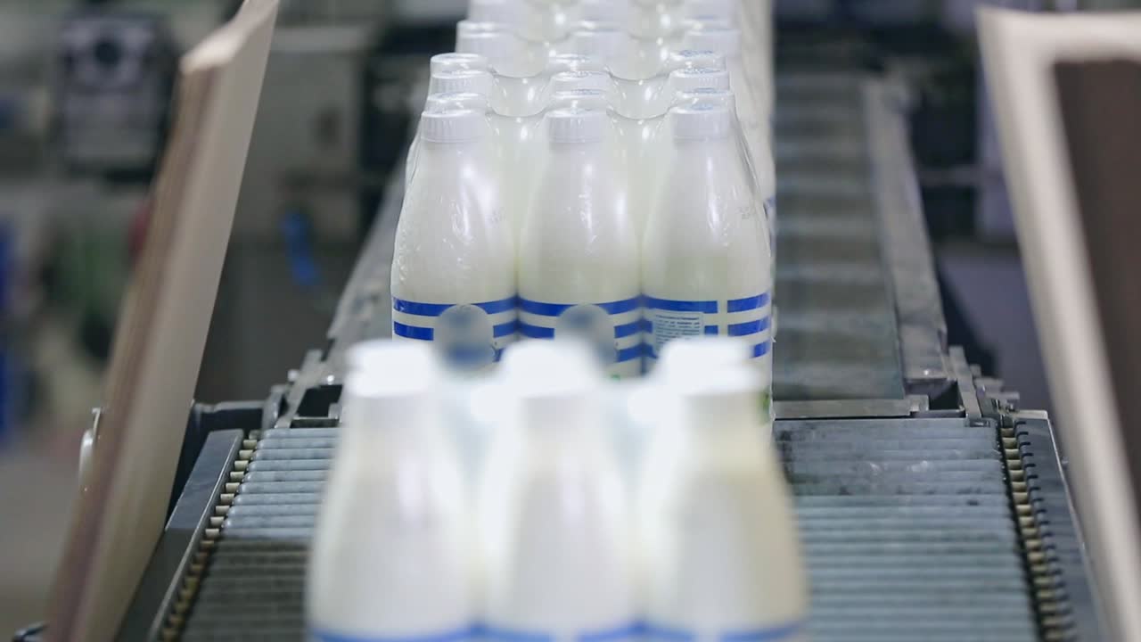 línea de envasado de leche. envasado de botellas de leche en línea transportadora. paquete de leche