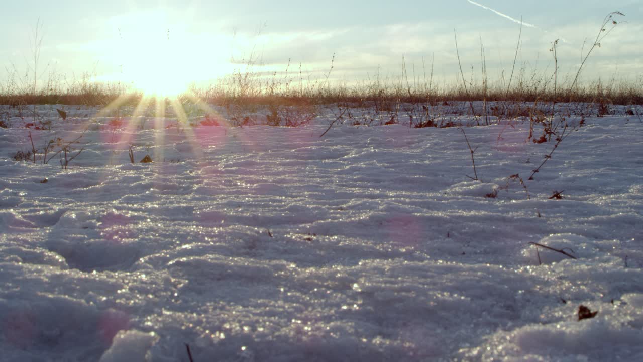 A horizontal establishing shot of the sun peaking over the horizon line on a crisp, cold day in the Wisconsin icy tundra.