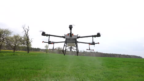 agriculture drone with nozzles spraying fertilizer on green farmland, modern farming concept