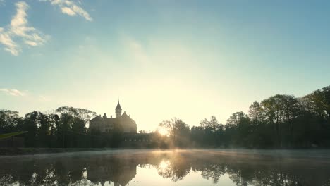 castle raduň in the czech republic, bathed in the warm glow of sunrise and mirrored in the still waters of a serene pond