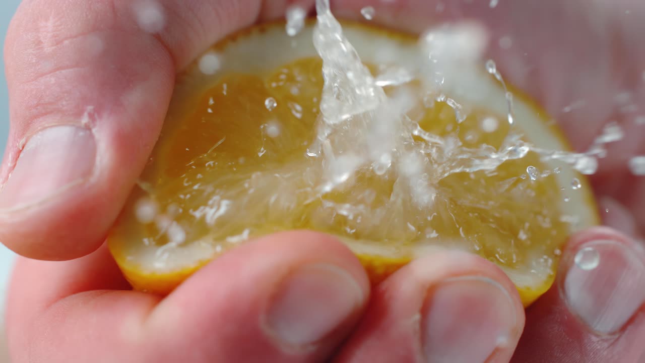 사람 은 공기 에 있는 주스 방울 과 함께 레몬 반 을 압축 하고 있다