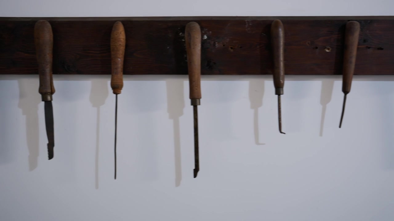 Utensili manuali vintage appesi a una rastrelliera di legno