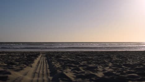 Wunderschöner,-Ruhiger-Und-Friedlicher-Sonnenuntergang-In-San-Diego,-Der-Eine-Im-Sand-Zurückgelassene-Reifenspur-Abschießt,-Während-Vögel-In-Die-Szene-Hinein--Und-Wieder-Herausfliegen