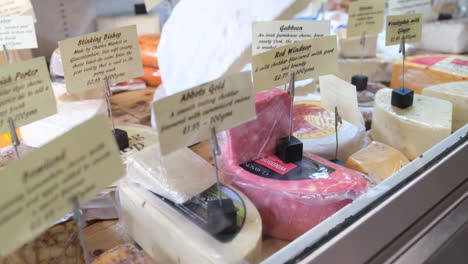 Shopkeeper-preparing-cheese-for-a-display-in-a-food-shop