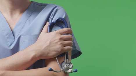close up of male doctor's hand holding a stethoscope while crossing his arms on green screen background in the hospital