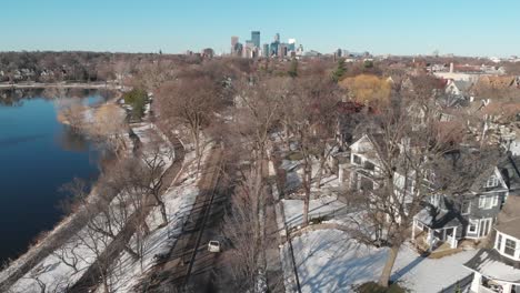 Aerial-footage-car-driving-on-a-street-heading-to-downtown-Minneapolis,-suburbs-on-sunny-day