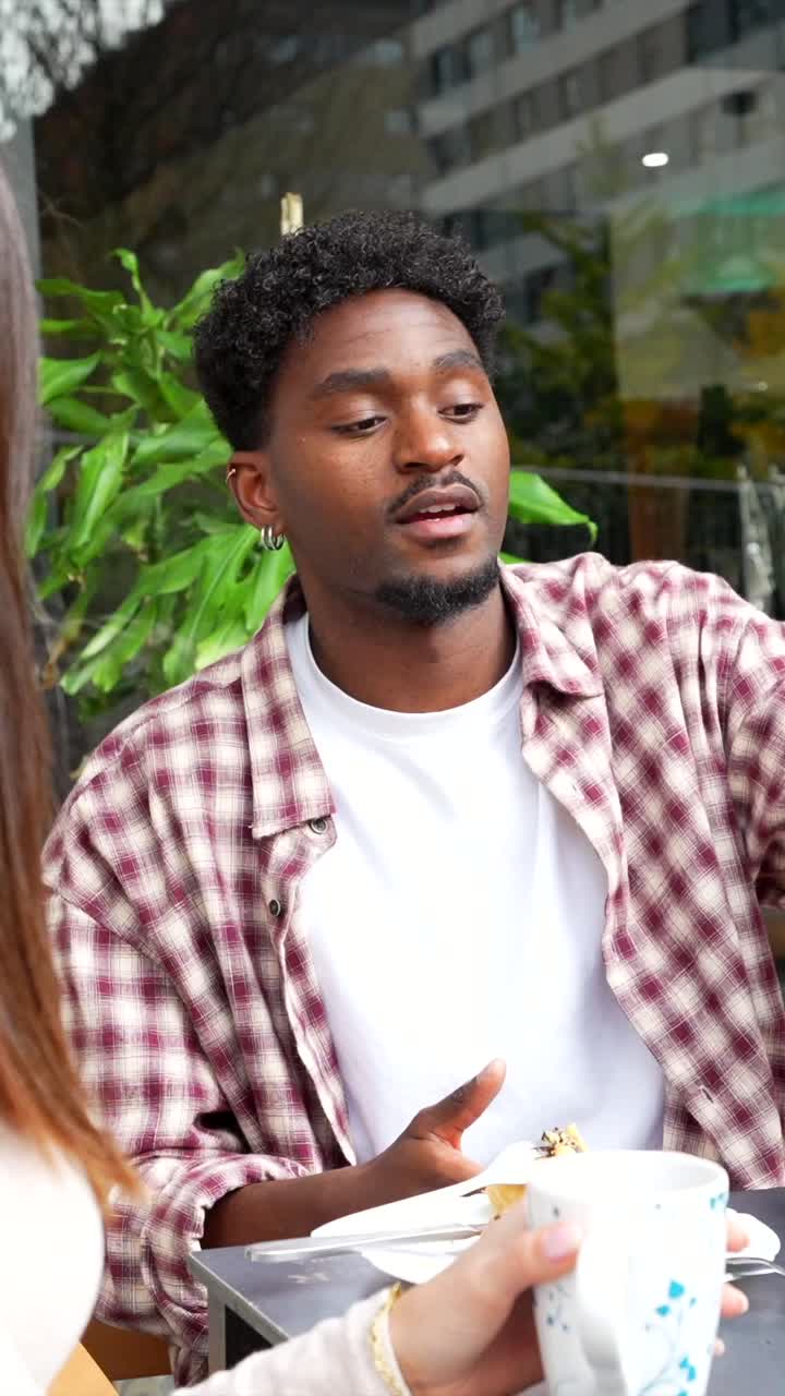 Young Man and Woman Having a Casual Conversation at an Outdoor Cafe