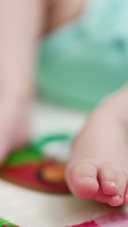 tiny feet of a baby lying on the bed on his back. child lies calmly on a colorful cover. close up. blue backdrop. vertical video