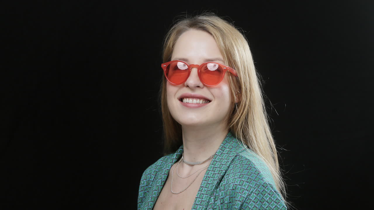 happy female with red sunglasses on black background