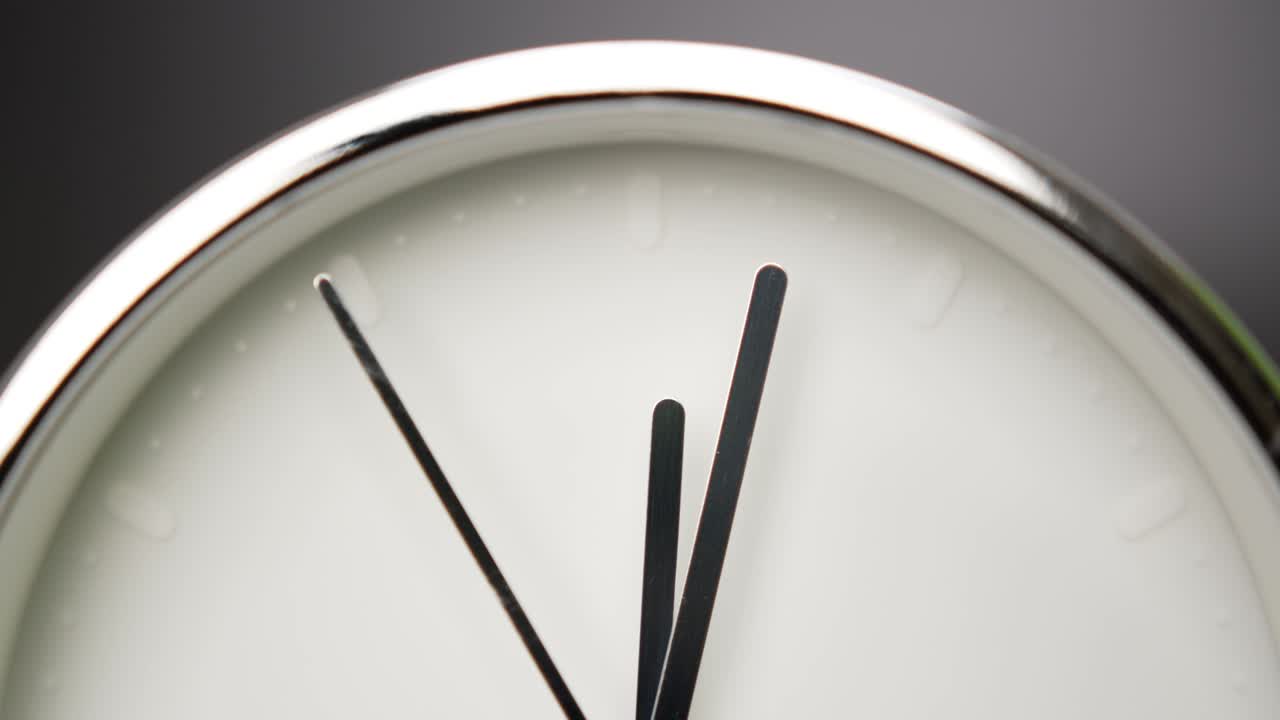 Twelve o'clock Silver Alarm clock on black background.