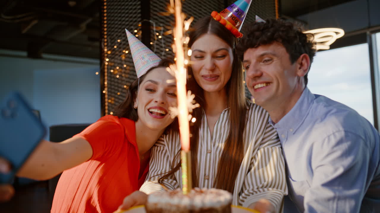 Aniversariantes tirando uma selfie e aproveitando a festa de perto com chapéus festivos. Equipe alegre