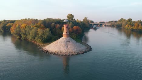 Drone-Aéreo-Orbitando-Alrededor-Del-Antiguo-Faro-De-Piedra-En-El-Río-Danubio-En-Un-Soleado-Día-De-Puesta-De-Sol-De-Otoño