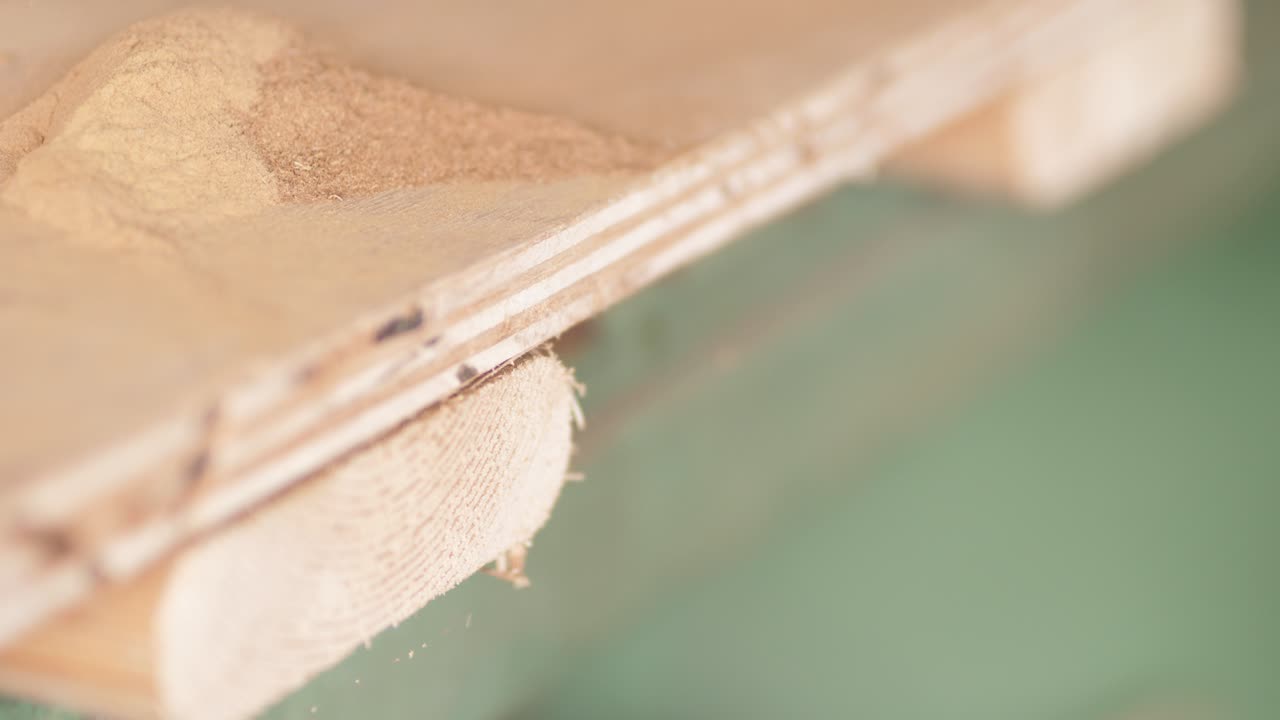 Scraping sawdust off table into container