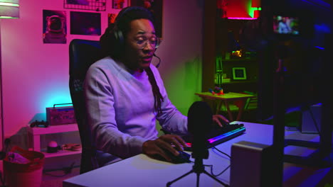 man playing video games in a dark room with purple lighting