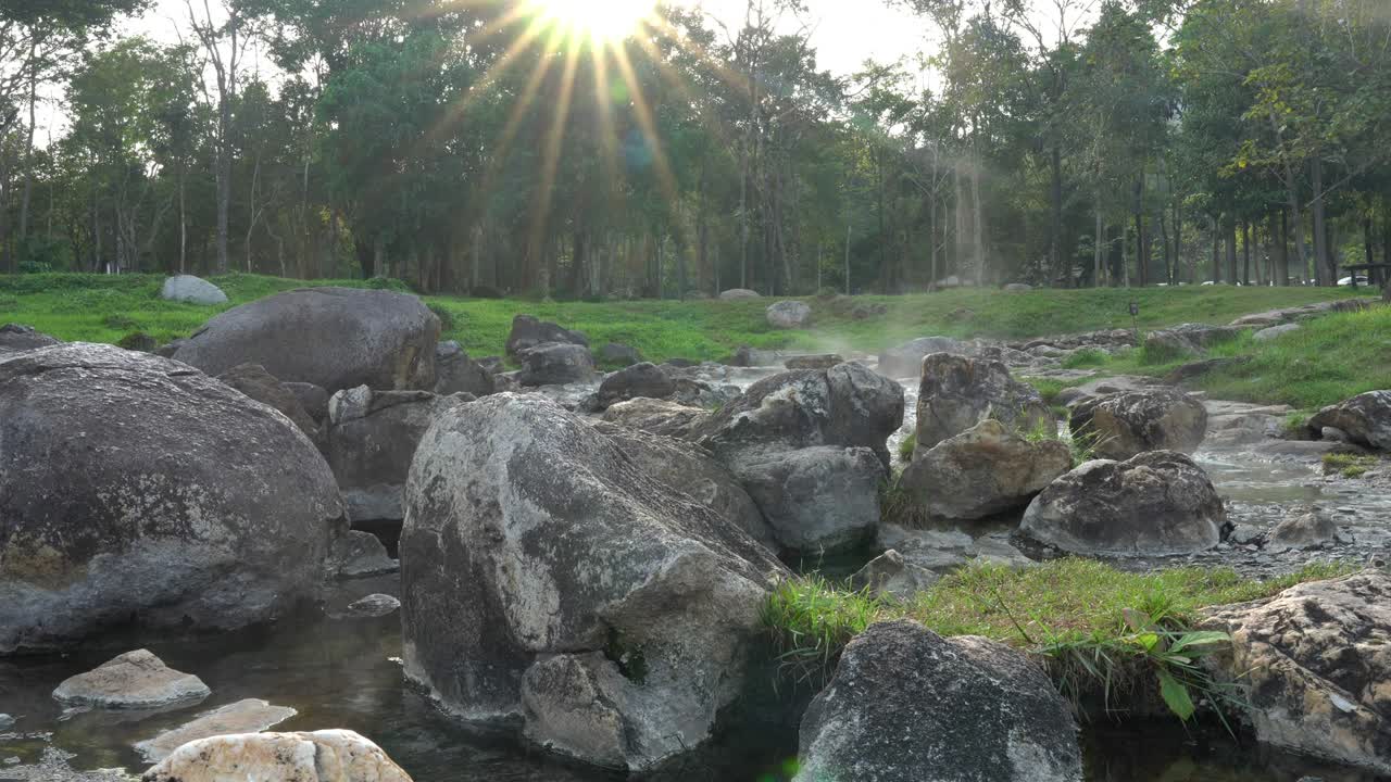 자연 온천의 4k 정적 은 빛과 불 아래의 바위를 따라 흐르고, 나무와 풀의 배경으로 증기가 떠다니고 있습니다. - chaesong 국립공원, lampang, 태국