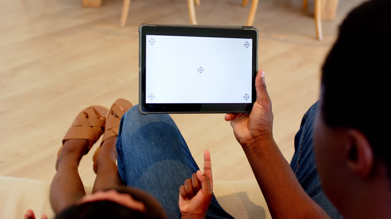 African American, Father and daughter relaxing at home, using tablet for interactive learning, copy