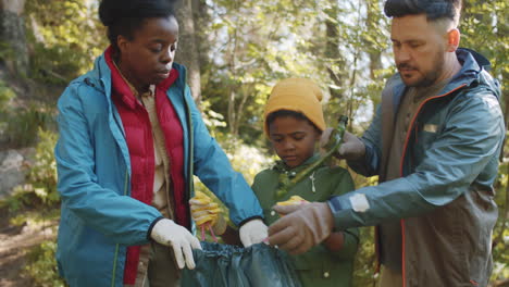 little boy and parents collecting garbage after camping