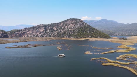 Filmen-Mit-Einer-Drohne-Eines-Vergnügungsbootes-Vor-Dem-Hintergrund-Eines-Grünen-Bergrahmens-In-Der-Türkei,-Der-Stadt-Dalyan-Turtle-Coast-Iztuzu