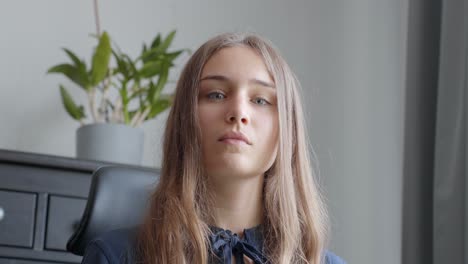 young woman looking straight into the camera, in a grey office