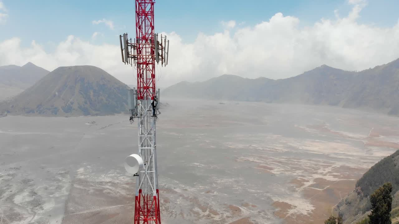 Uomo che scala un'antenna a Cemorolawang, Giava Orientale, Indonesia