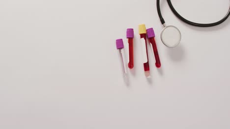 Video-of-close-up-of-stethoscope-with-test-tubes-on-pink-background