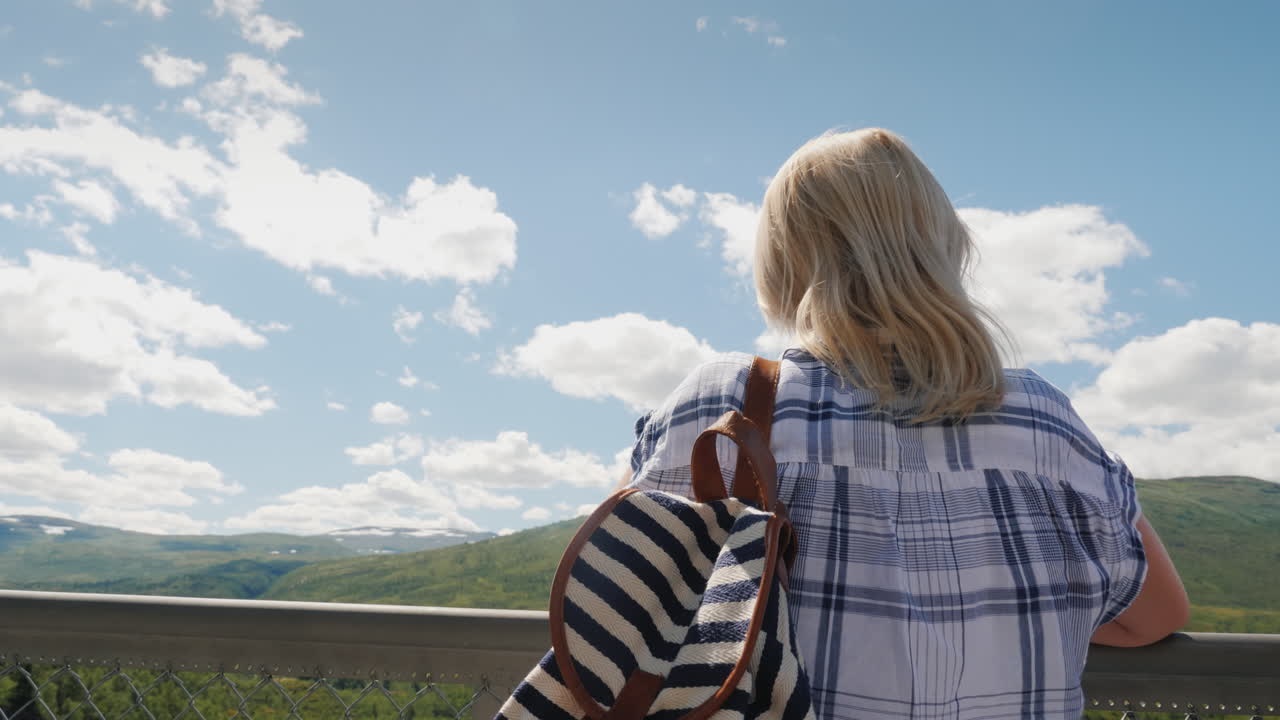 한 여성이 노르웨이 스칸디나비아의 인상적인 아름다움에 있는 woringsfossen의 장엄한 폭포를 바라보고 있습니다.