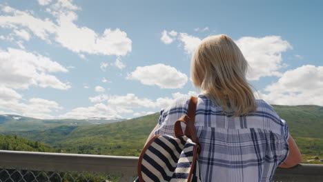 a woman looks at the majestic waterfall of woringsfossen in norway impressive beauty of scandinavian