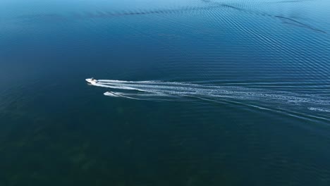 cinematic aerial drone footage of water skier following boat along glassy fornells bay in menorca, spain