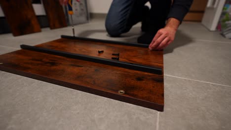 closeup of man assembling wooden table, screwing screws