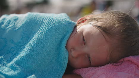 Cute-little-child-awakes-napping-on-deck-chair-on-beach