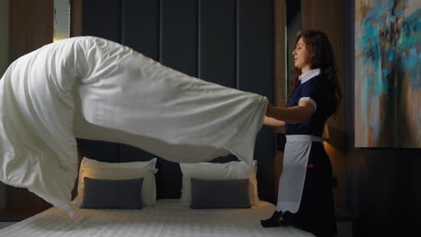 maid making a bed in a hotel room