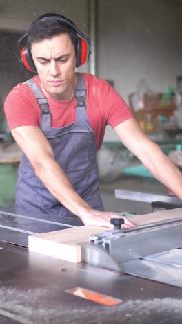 man cutting wood with a table saw in a workshop