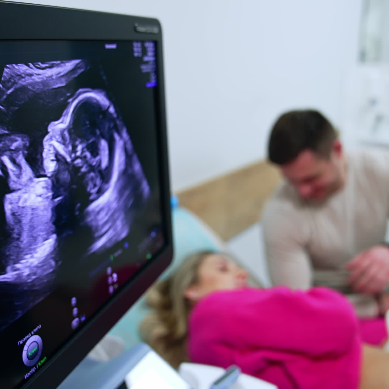 Ecografia di un feto sullo schermo di un macchinario. Coppia sposata sullo sfondo. Esame di gravidanza e osservazione in clinica