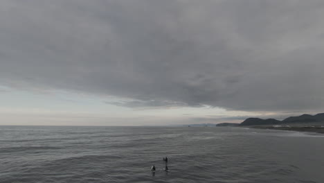 surfers on a cloudy pacific coast